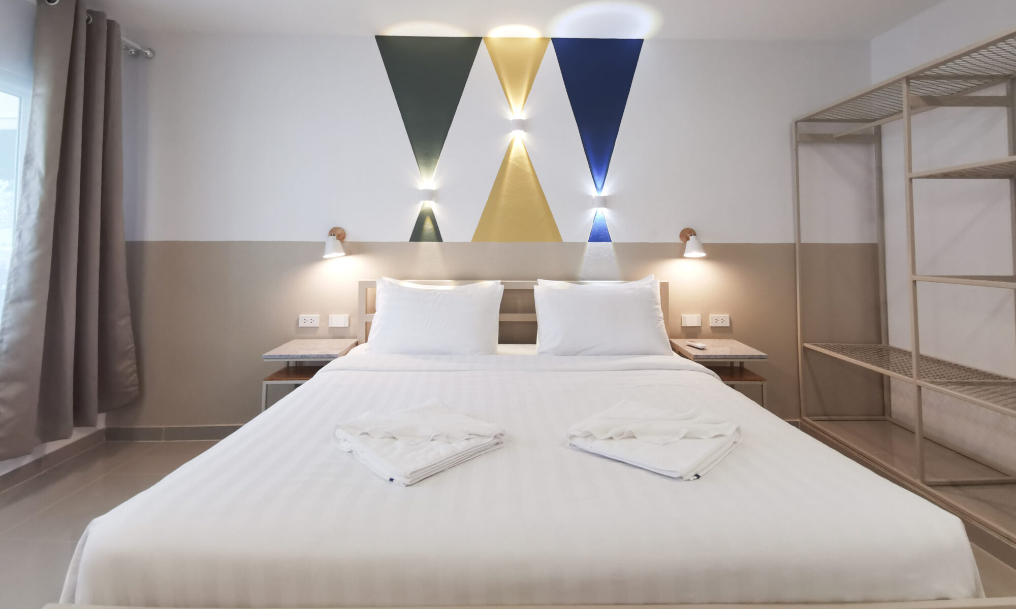Bright modern bedroom at Thepprasit Cosy Twin with white linens, folded towels, geometric wall art, and a famously comfortable mattress.