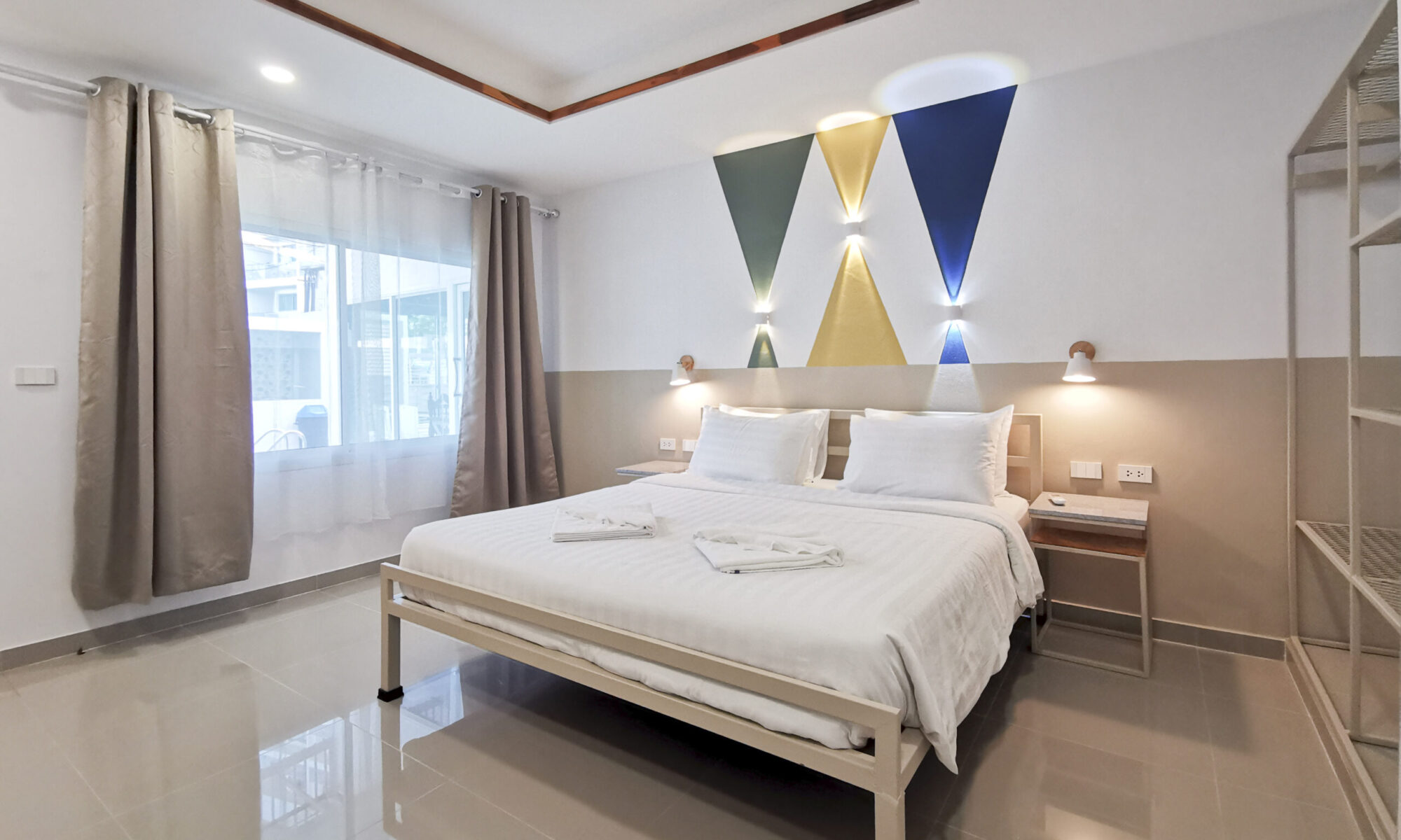 Bright, modern bedroom at Thepprasit Cosy Twin featuring soft linens, geometric wall art, and natural light for a peaceful stay.